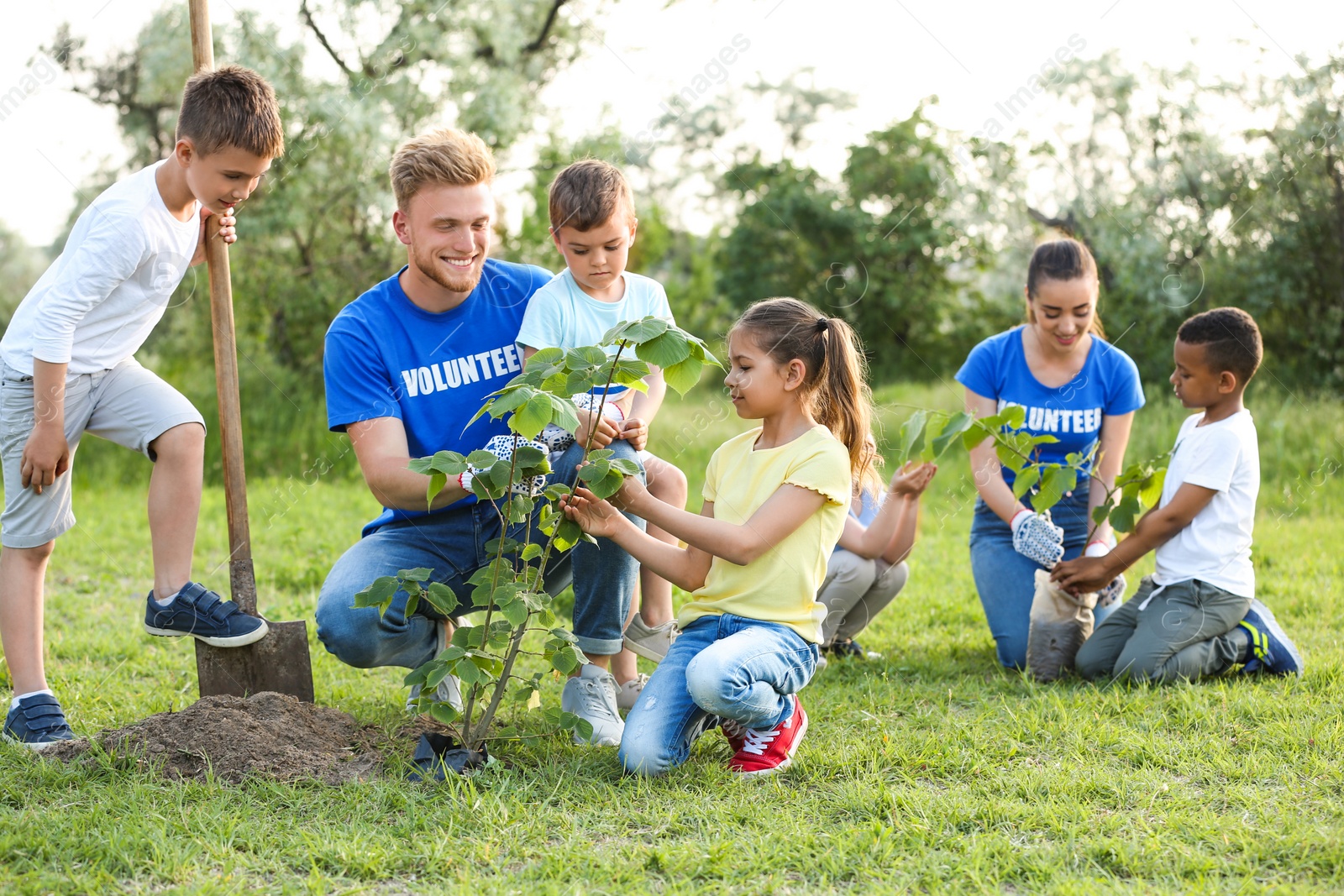 Photo of Kids planting trees with volunteers in park