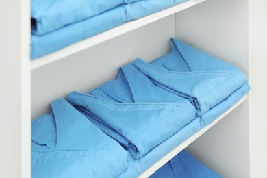 Light blue medical uniforms on white rack