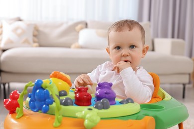Portrait of cute baby with toy walker at home. Learning to walk