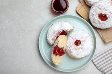 Delicious donuts with jelly and powdered sugar served on light grey table, flat lay. Space for text