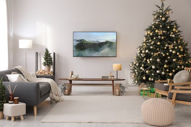 Photo of Modern TV set on light wall in room decorated for Christmas