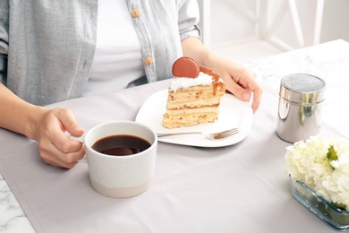 Woman eating delicious homemade cake with caramel sauce at table