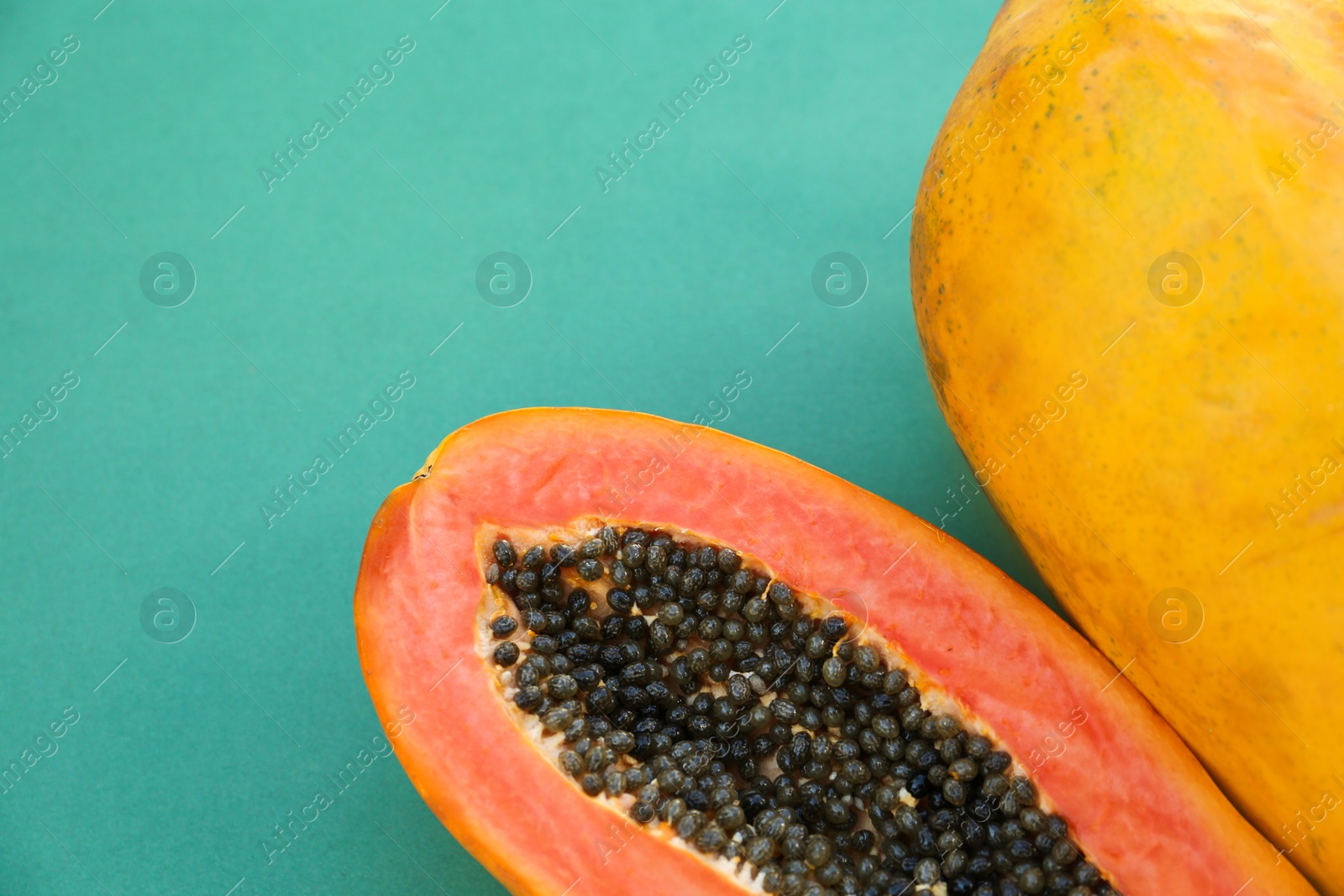 Photo of Fresh ripe cut and whole papaya fruits on light blue background, flat lay. Space for text