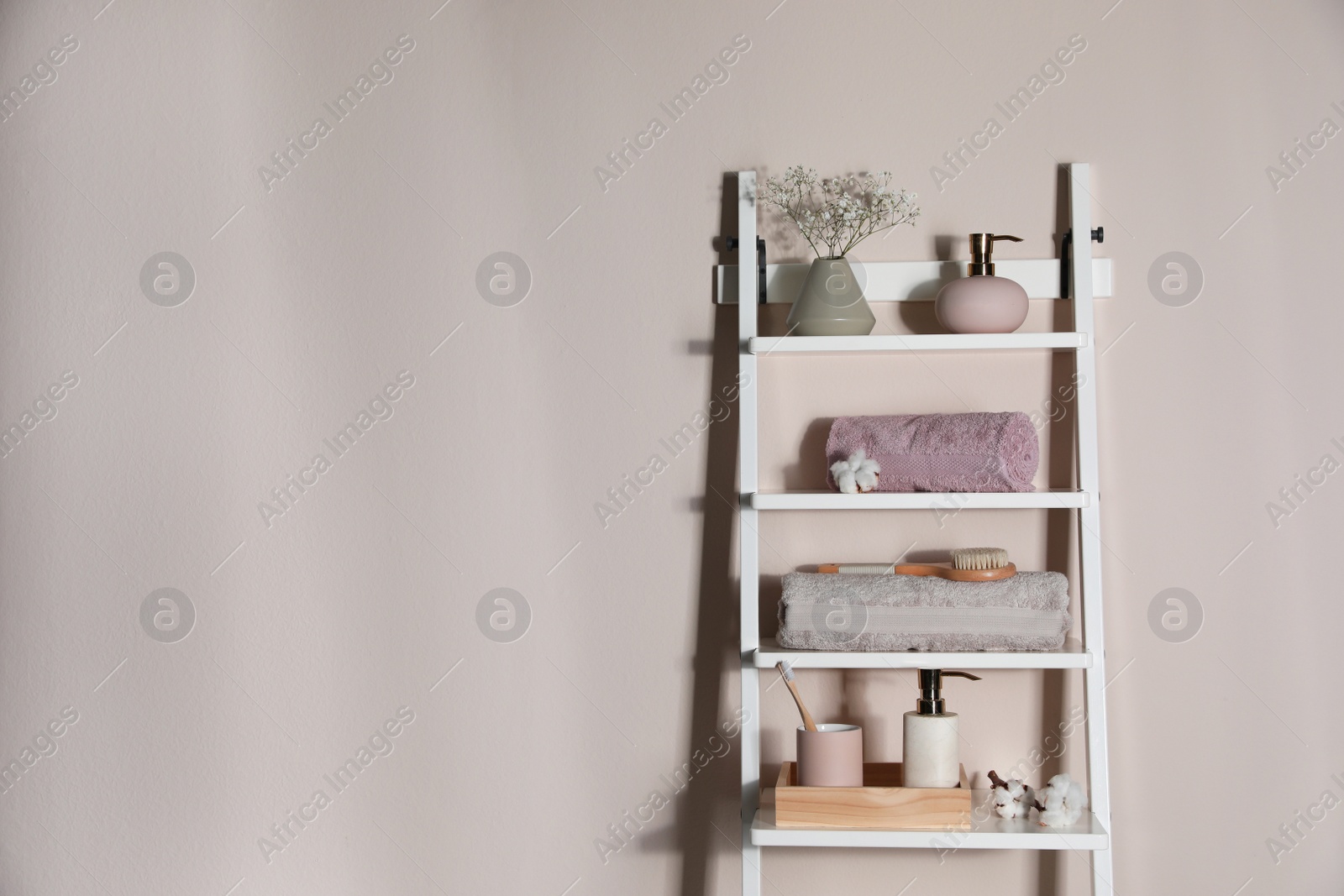 Photo of Shelving unit with toiletries near light wall indoors, space for text. Bathroom interior element