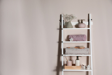 Photo of Shelving unit with toiletries near light wall indoors, space for text. Bathroom interior element