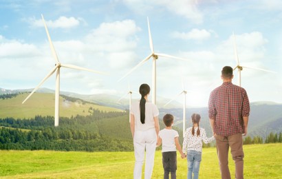 Family with children looking at wind energy turbines on sunny day