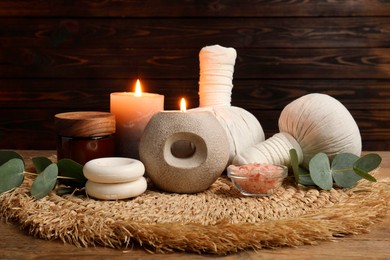 Photo of Aromatherapy. Scented candles, eucalyptus branches and spa products on wooden table