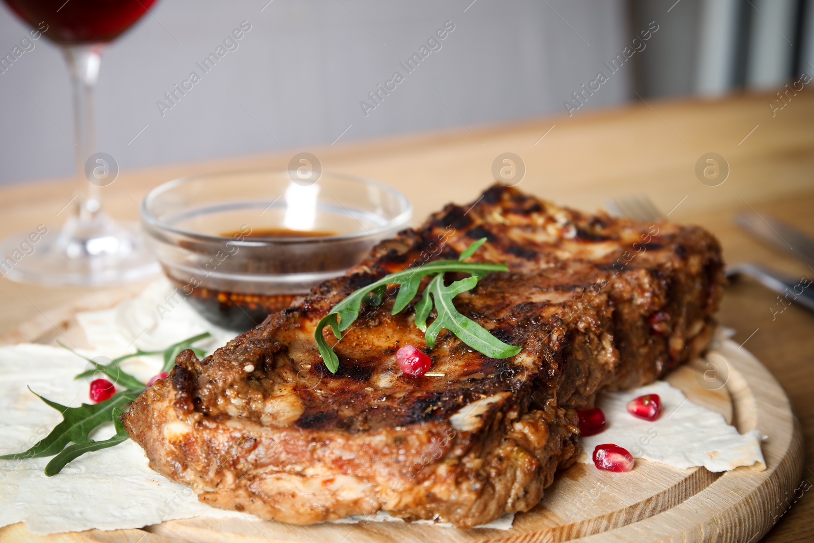 Photo of Delicious grilled ribs on wooden board, closeup