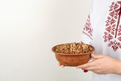 Photo of Woman in slavic shirt holding bowl with traditional kutia, closeup. Space for text