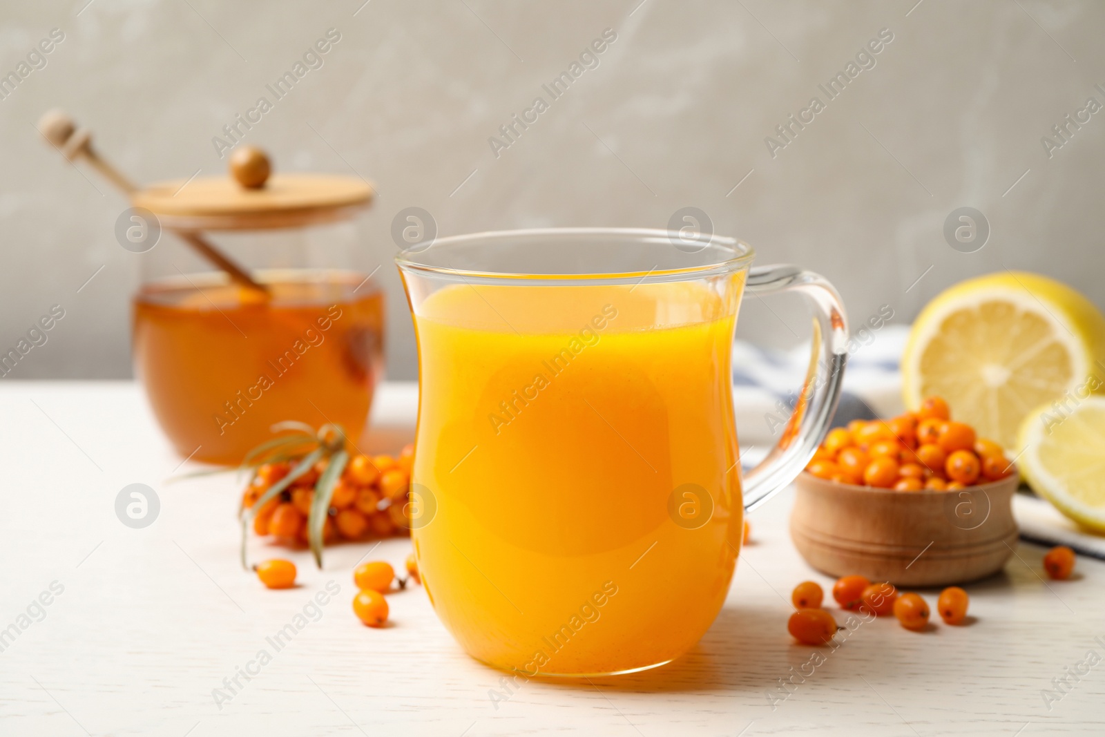 Photo of Fresh sea buckthorn tea on white wooden table, closeup