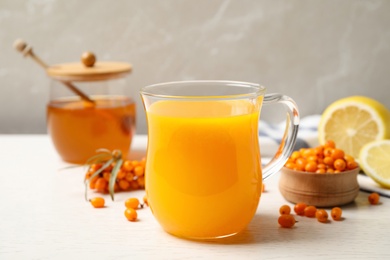 Photo of Fresh sea buckthorn tea on white wooden table, closeup