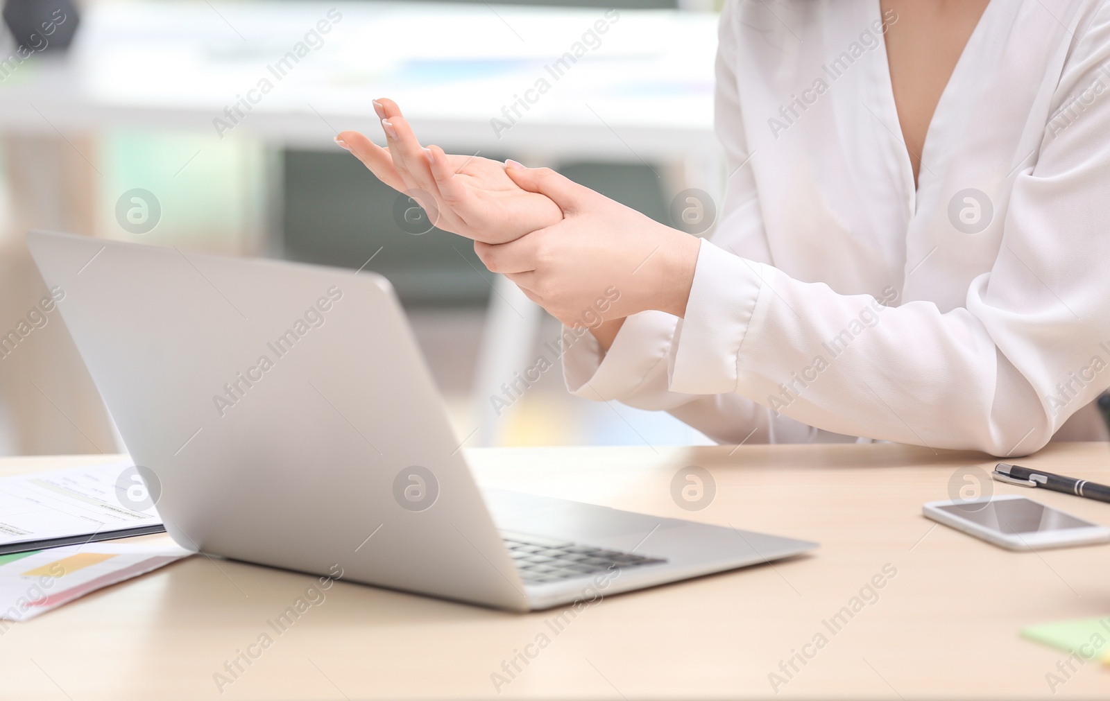 Photo of Young woman suffering from wrist pain in office