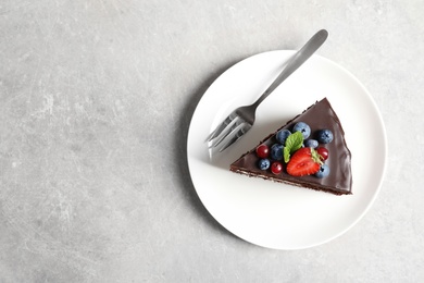 Photo of Plate with slice of chocolate sponge berry cake on grey background, top view