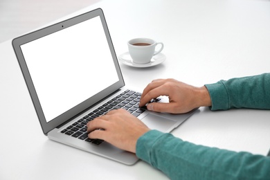 Photo of Young man working with modern laptop at table, closeup. Mockup for design