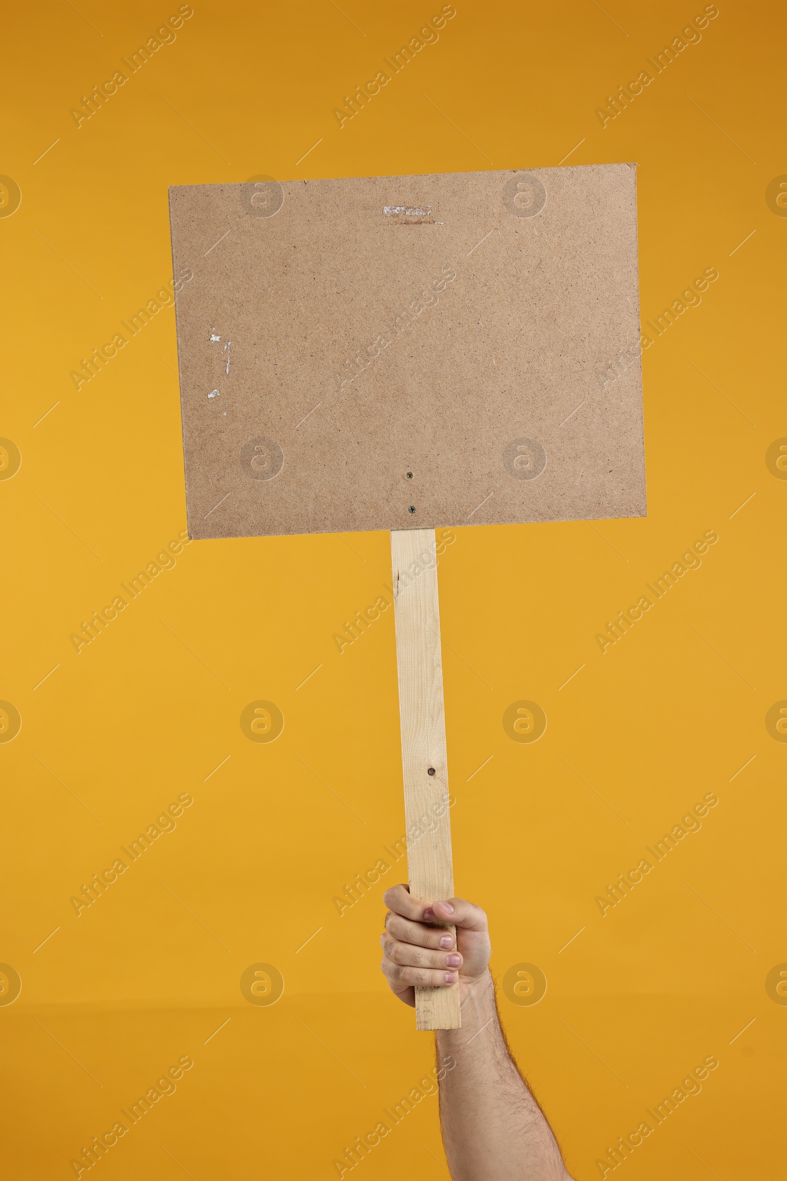 Photo of Man holding blank sign on orange background, closeup. Space for text