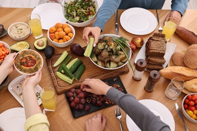 Friends eating vegetarian food at wooden table indoors, closeup