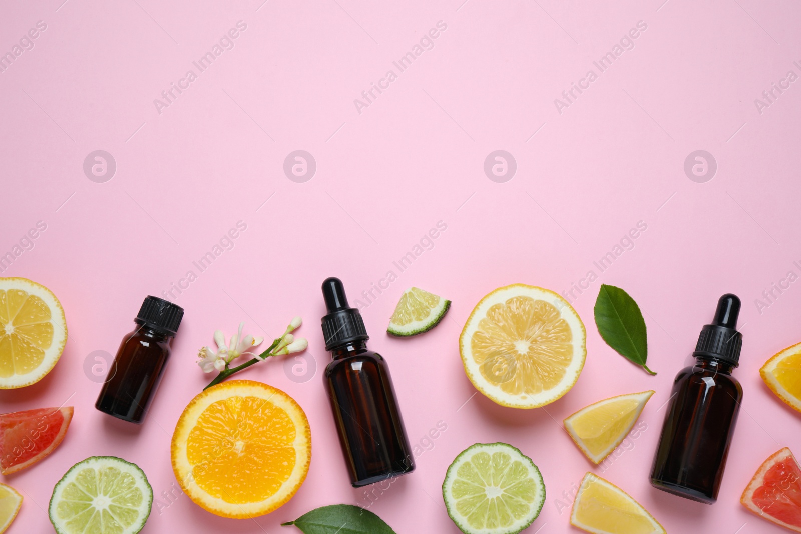 Photo of Flat lay composition with bottles of citrus essential oil on pink background. Space for text