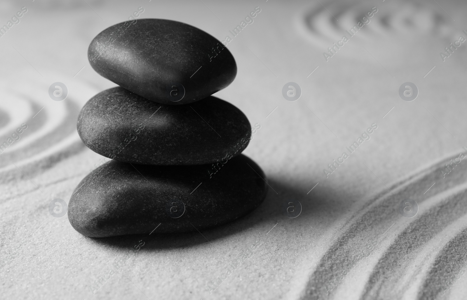 Photo of Stacked zen garden stones on sand with pattern, space for text. Meditation and harmony