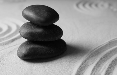 Photo of Stacked zen garden stones on sand with pattern, space for text. Meditation and harmony