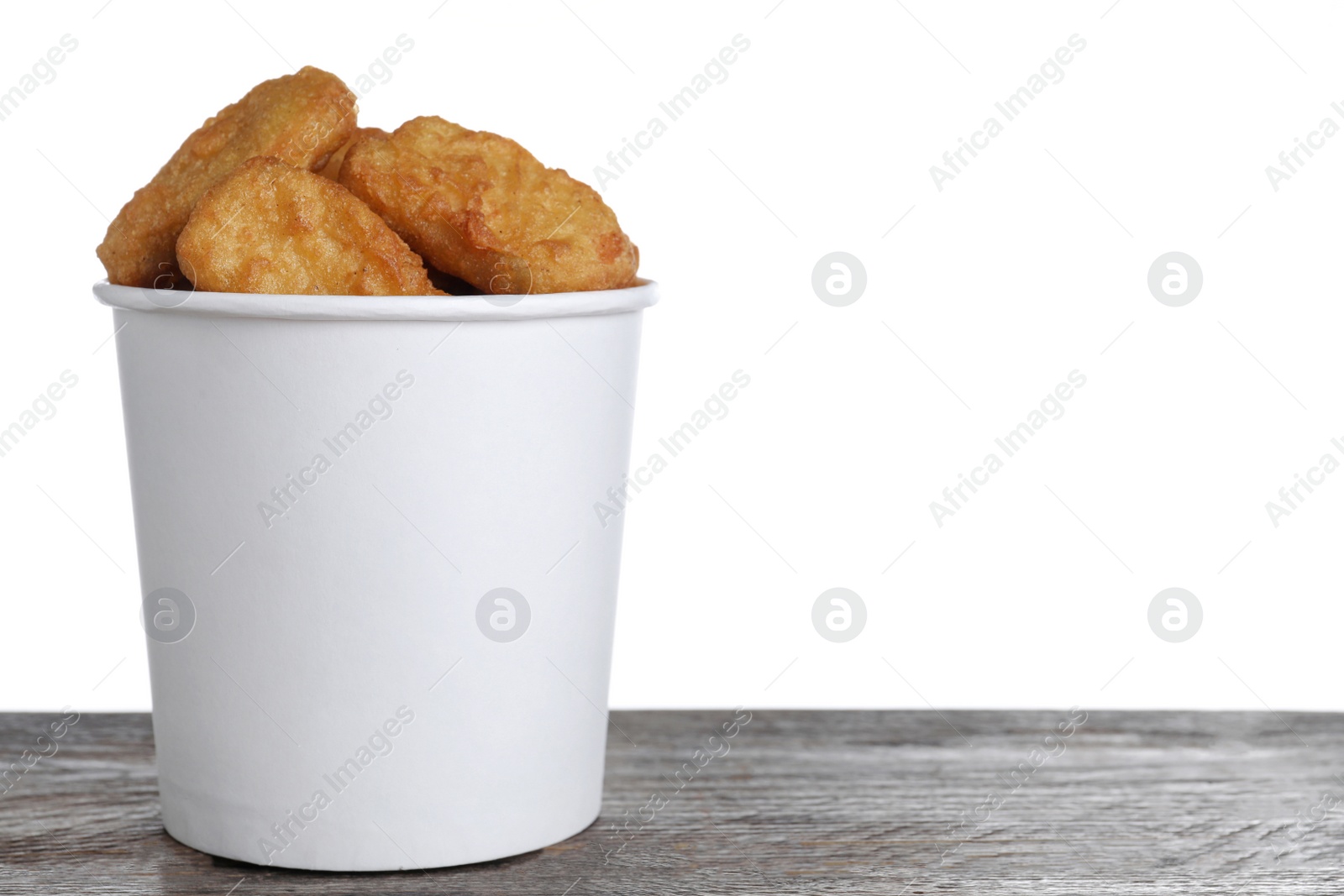 Photo of Bucket with tasty chicken nuggets on wooden table against white background. Space for text