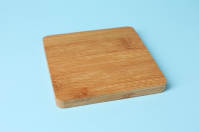 Photo of Wooden cup coaster on light blue background
