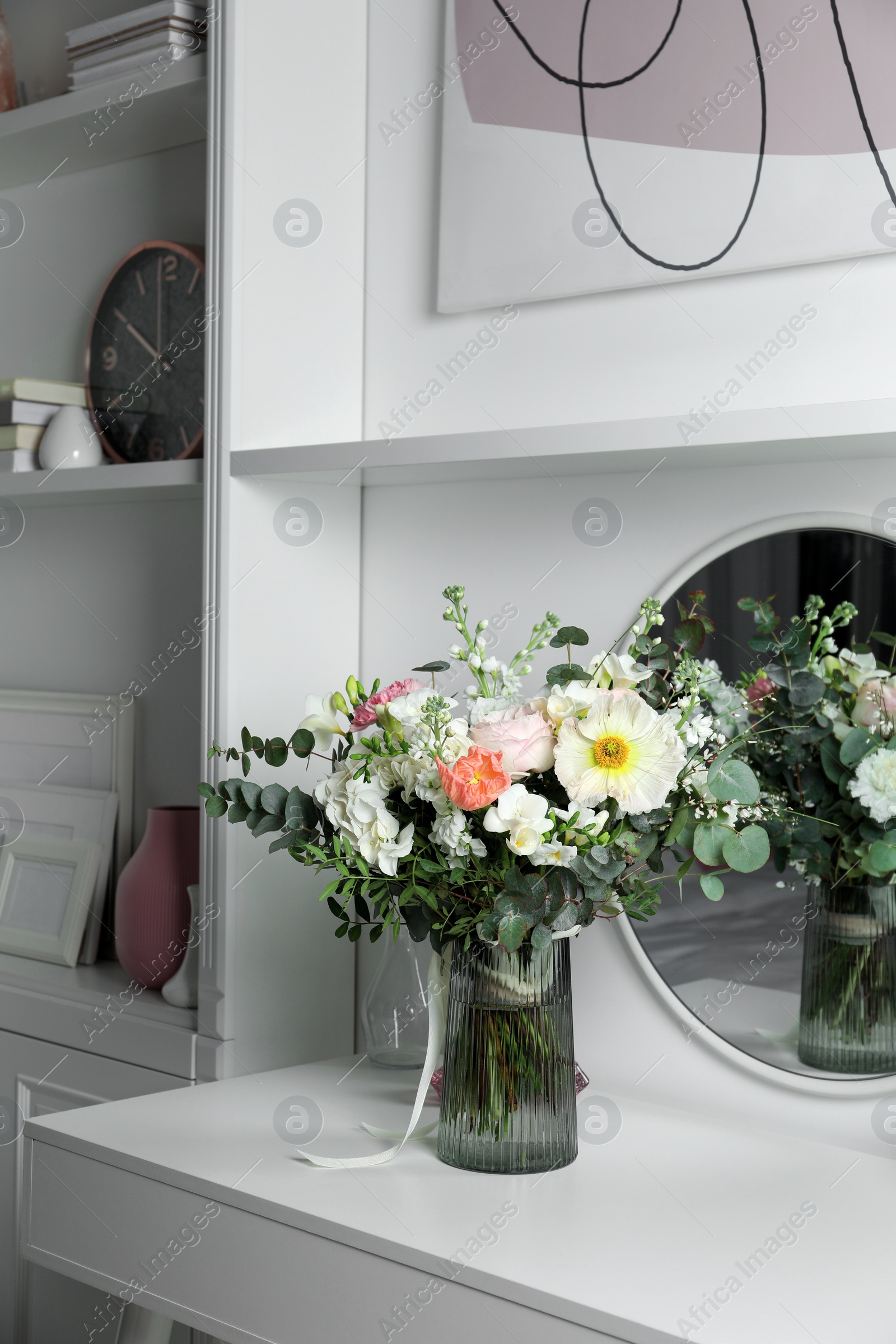 Photo of Bouquet of beautiful flowers on white table near mirror indoors