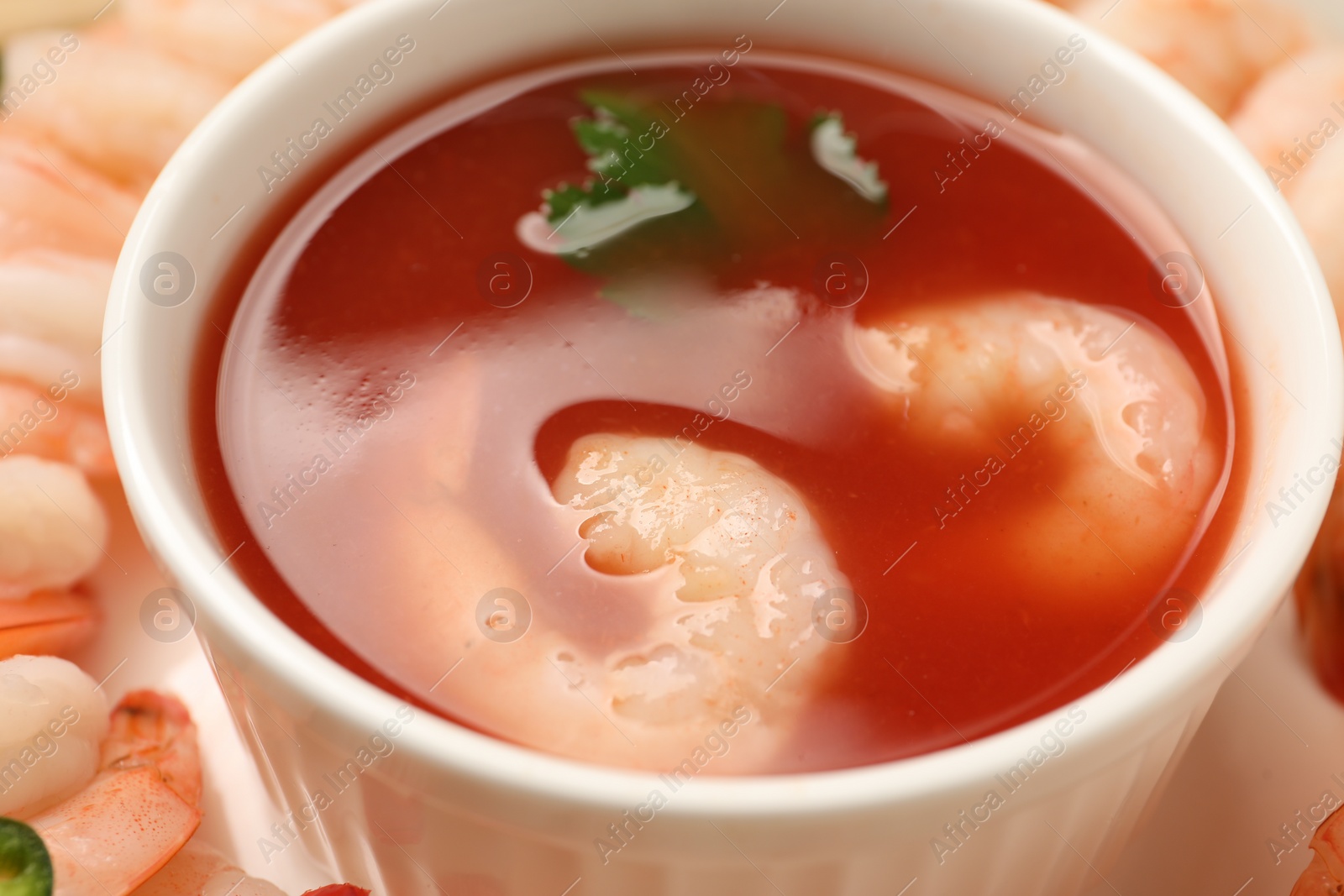 Photo of Tasty boiled shrimps with cocktail sauce, chili and parsley on table, closeup