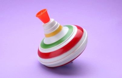 Photo of One bright spinning top on violet background. Toy whirligig