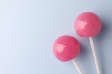 Photo of Tasty lollipops on light blue background, flat lay. Space for text