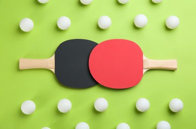 Photo of Ping pong rackets and balls on green background, flat lay