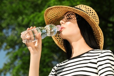 Photo of Beautiful young woman drinking water outdoors. Refreshing drink