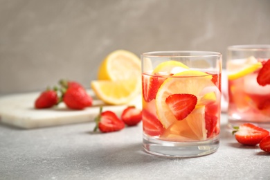 Photo of Tasty refreshing drink with strawberries and lemon on light grey table. Space for text