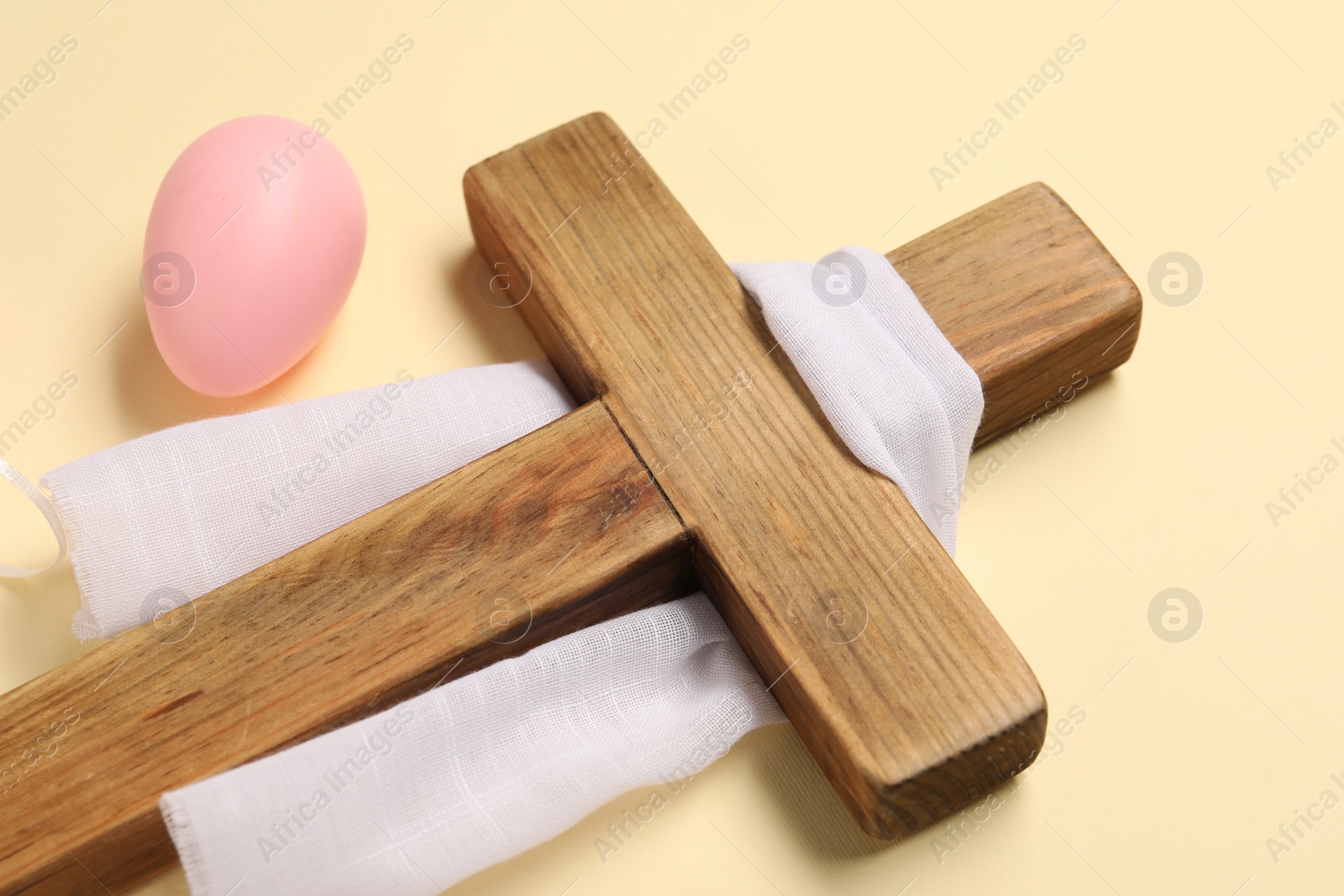 Photo of Wooden cross, white cloth and painted Easter eggs on beige background