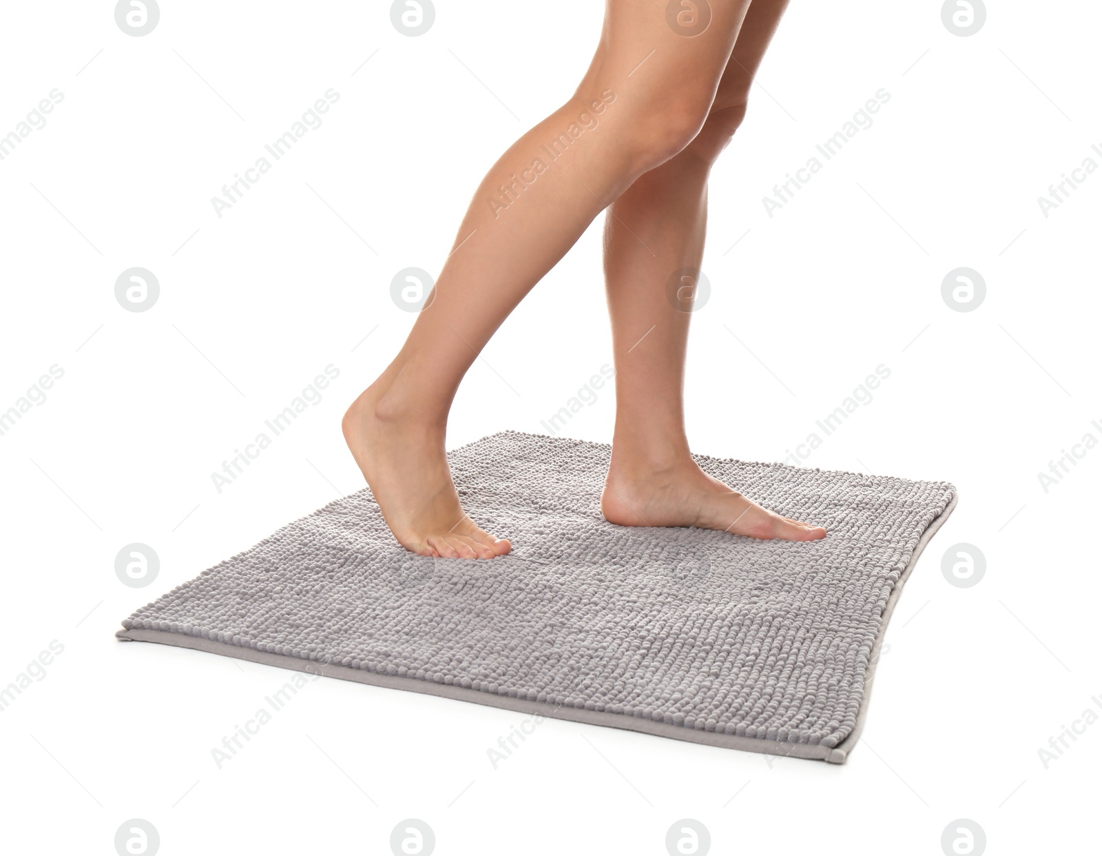 Photo of Woman standing on soft grey bath mat against white background, closeup