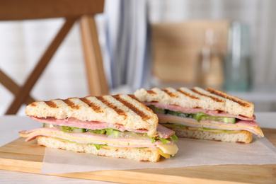 Photo of Tasty sandwich with ham on wooden board indoors