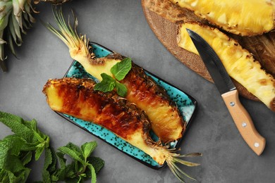 Photo of Tasty grilled and fresh pineapple pieces on grey textured table, flat lay