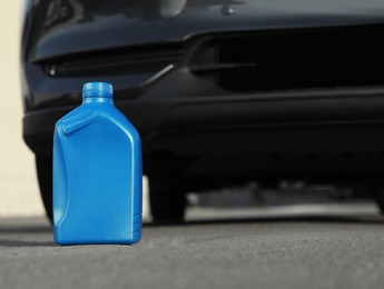 Blue canister with motor oil near car on asphalt road