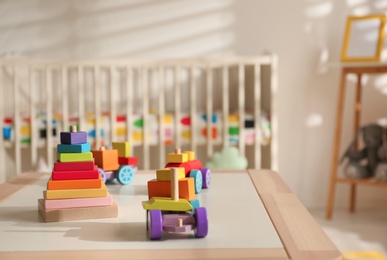 Bright wooden toys on table in cozy baby room interior