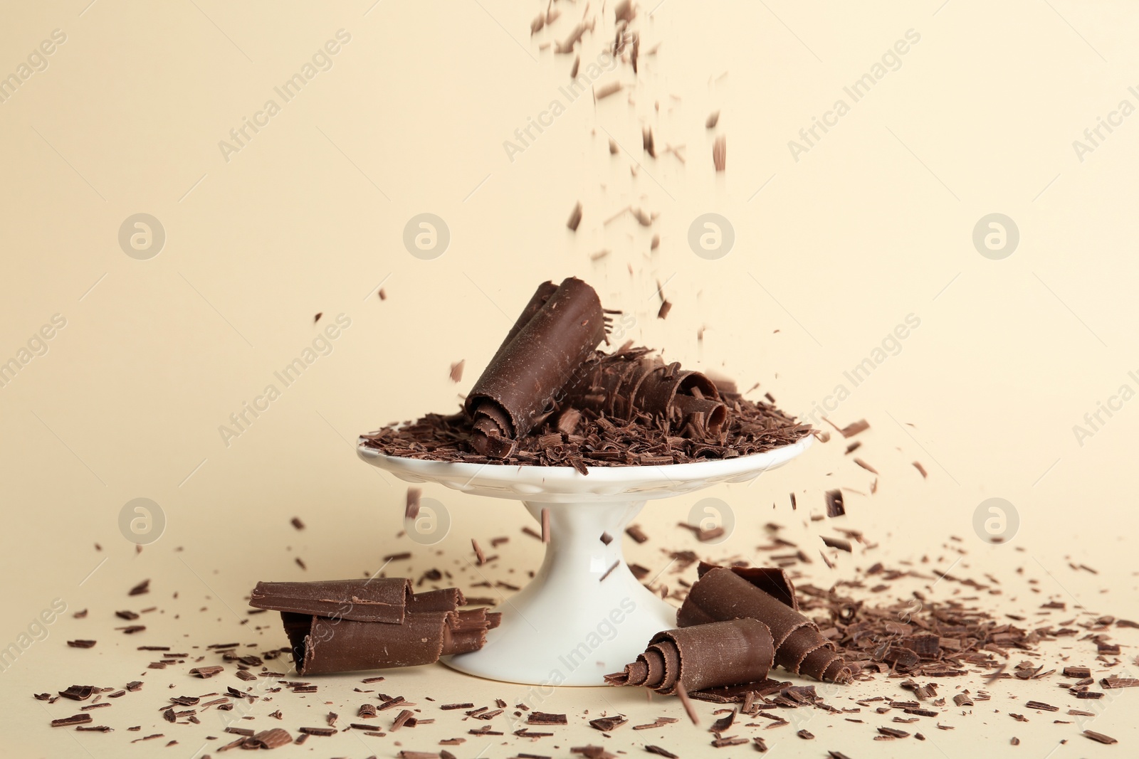 Photo of Sprinkling chocolate curls onto dessert stand on color background