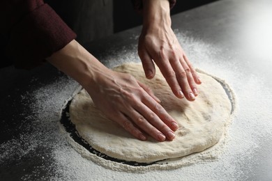 Photo of Woman kneading pizza dough at table, closeup