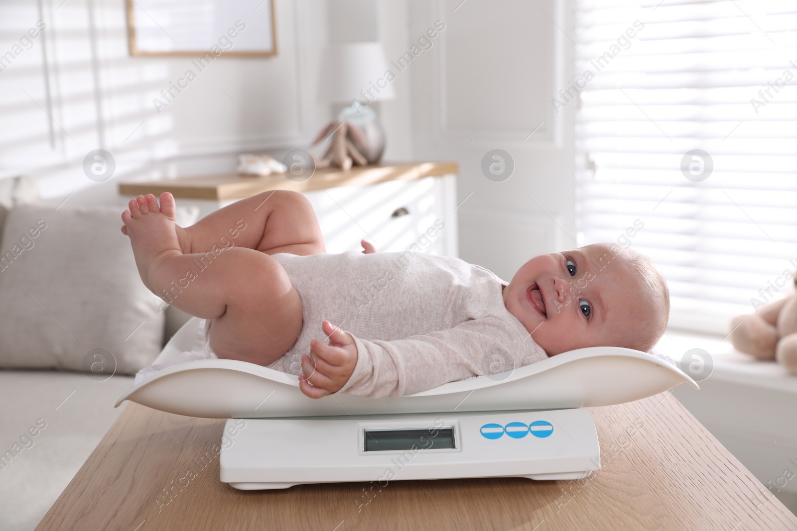 Photo of Cute little baby lying on scales at home