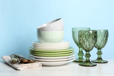 Photo of Beautiful ceramic dishware, glasses and cutlery on white marble table