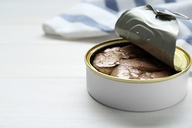 Open tin can of tasty cod liver on white wooden table, closeup. Space for text