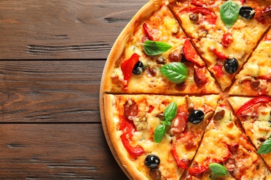 Photo of Delicious pizza with olives and sausages on wooden table, top view