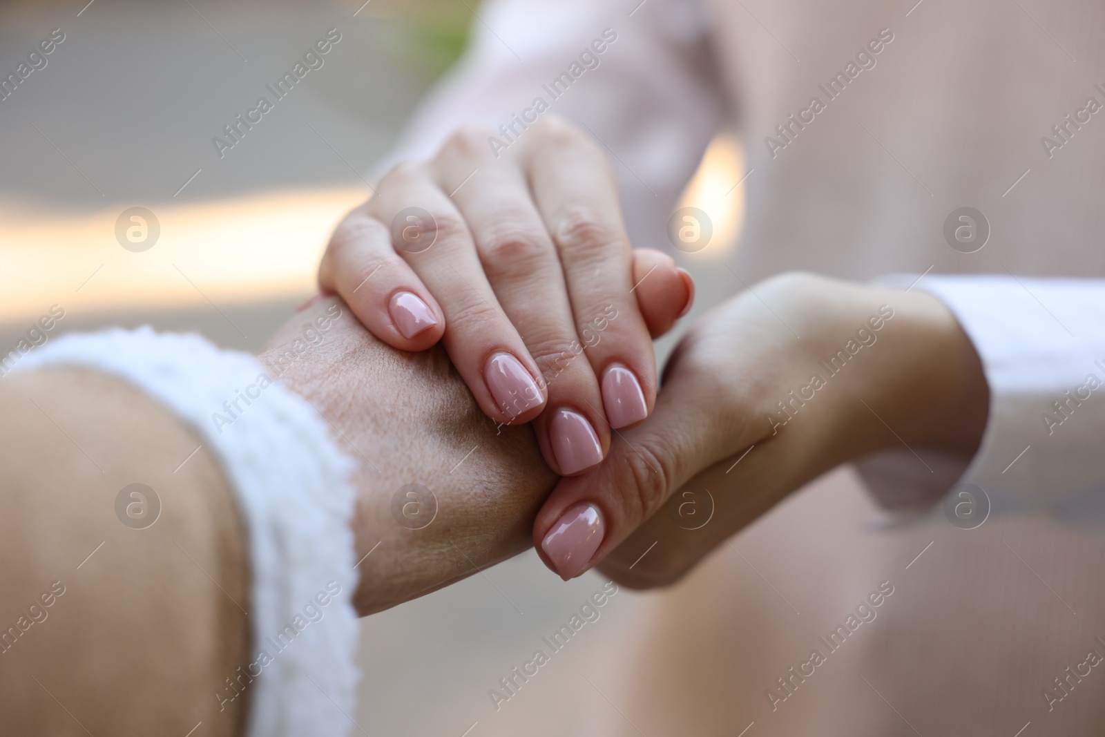 Photo of Trust and support. Women joining hands outdoors, closeup