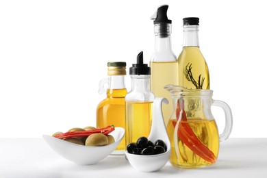 Photo of Many different cooking oils and olives on white background