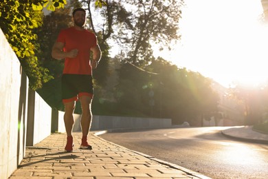 Photo of Happy man running outdoors on sunny day. Space for text