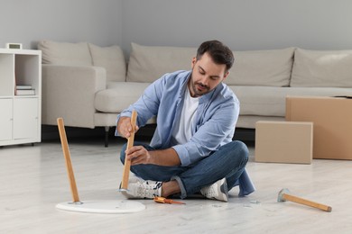 Photo of Man assembling table on floor at home