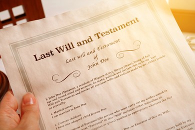 Image of Woman holding Last Will and Testament at table, closeup