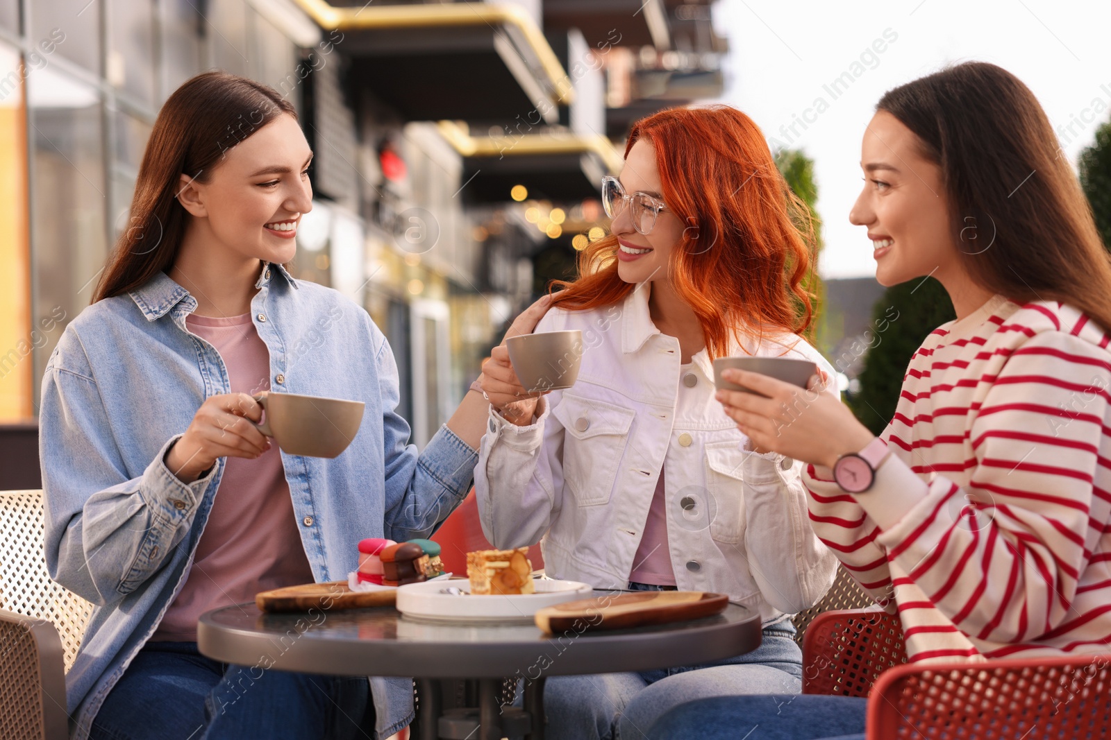 Photo of Happy friends talking and drinking coffee in outdoor cafe